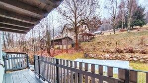 Eine Holzdar Terrasse mit Metallgeländer, mit Blick auf eine ländliche Landschaft mit Häusern und Bäumen.