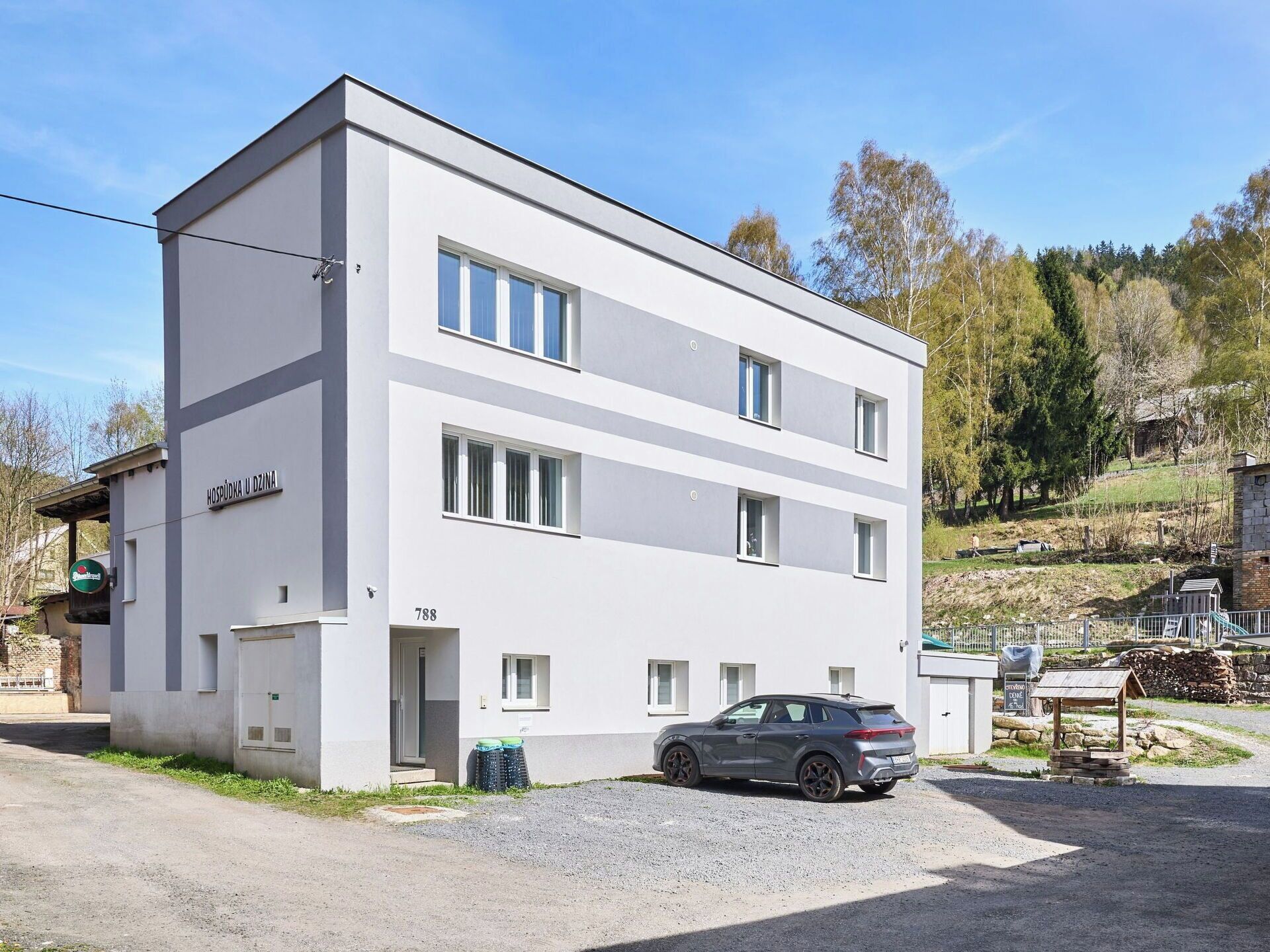 A modern two-story building with a sign reading 'HOSPODSKA U DZINA' and the number '788' on the facade.