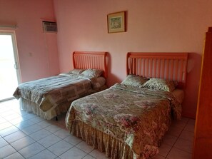 Un dormitorio con dos camas, una ventana, una puerta y un cuadro en la pared.