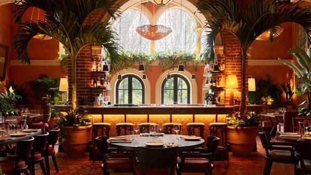 A restaurant with round tables, chairs, and potted plants. - Your Place - 2 bedroom Mews House in Notting Hill (London)