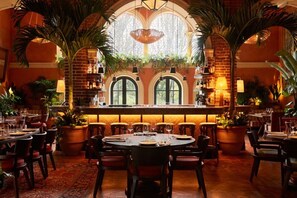 Een restaurant met ronde tafels, stoelen en potplanten.
