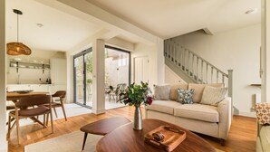 A spacious living area with a sofa, coffee table, and dining table. - Your Place - 2 bedroom Mews House in Notting Hill (London)