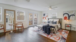 A spacious bedroom with a large bed, two chairs, a mirror, and artwork on the walls. - Wonderful 3-bedroom house with AC in vibrant New Orleans (New Orleans)