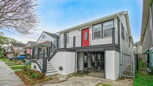 A two-story residential building with a red door, a front staircase, and a gated entrance. - Wonderful 3-bedroom house with AC in vibrant New Orleans (New Orleans)