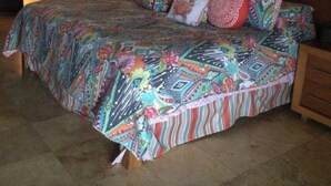 Une chambre à coucher avec un grand lit, une tête de lit en bois, une table de chevet et une lampe fixée au mur.