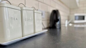 A kitchen counter with three containers labeled 'TEA,' 'COFFEE,' and 'SUGAR.' - Shoreditch Apartments by PrimeCityHosts F6 (Greater London)