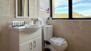 A bathroom with a sink, mirror, toilet, and window. - Shoreditch Apartments by PrimeCityHosts F6 (Greater London)