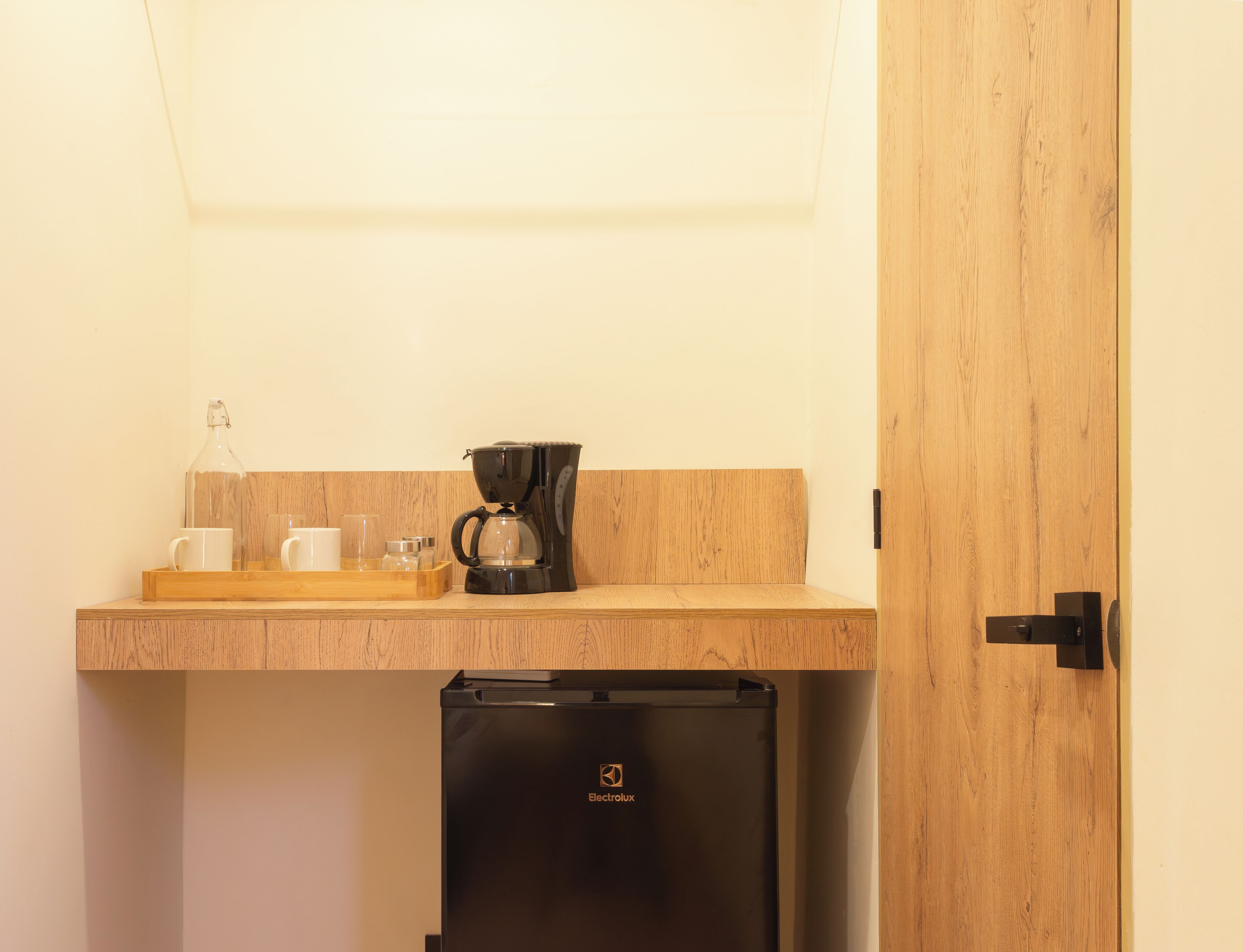 Una kitchenette con cafetera, refrigerador y encimera de madera.