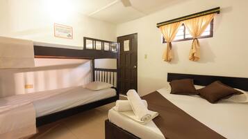 A room with two beds, one with a bunk bed and the other with a single bed. There is a door, a window with curtains, and a sign on the wall.
