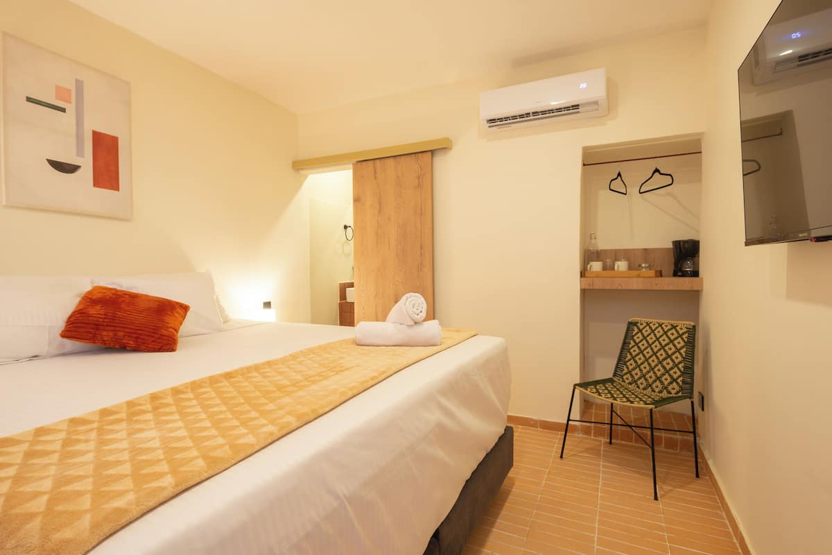 A hotel room with a bed, a chair, a wardrobe, and a television.