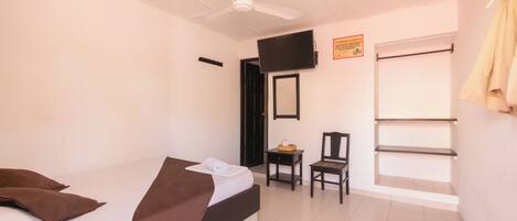 A hotel room with a bed, a chair, a television, and a window.