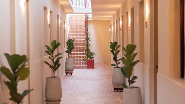 A corridor with potted plants, a staircase, and a balcony with railings. - Casa del Huesped by 3Villas (Santa Marta)