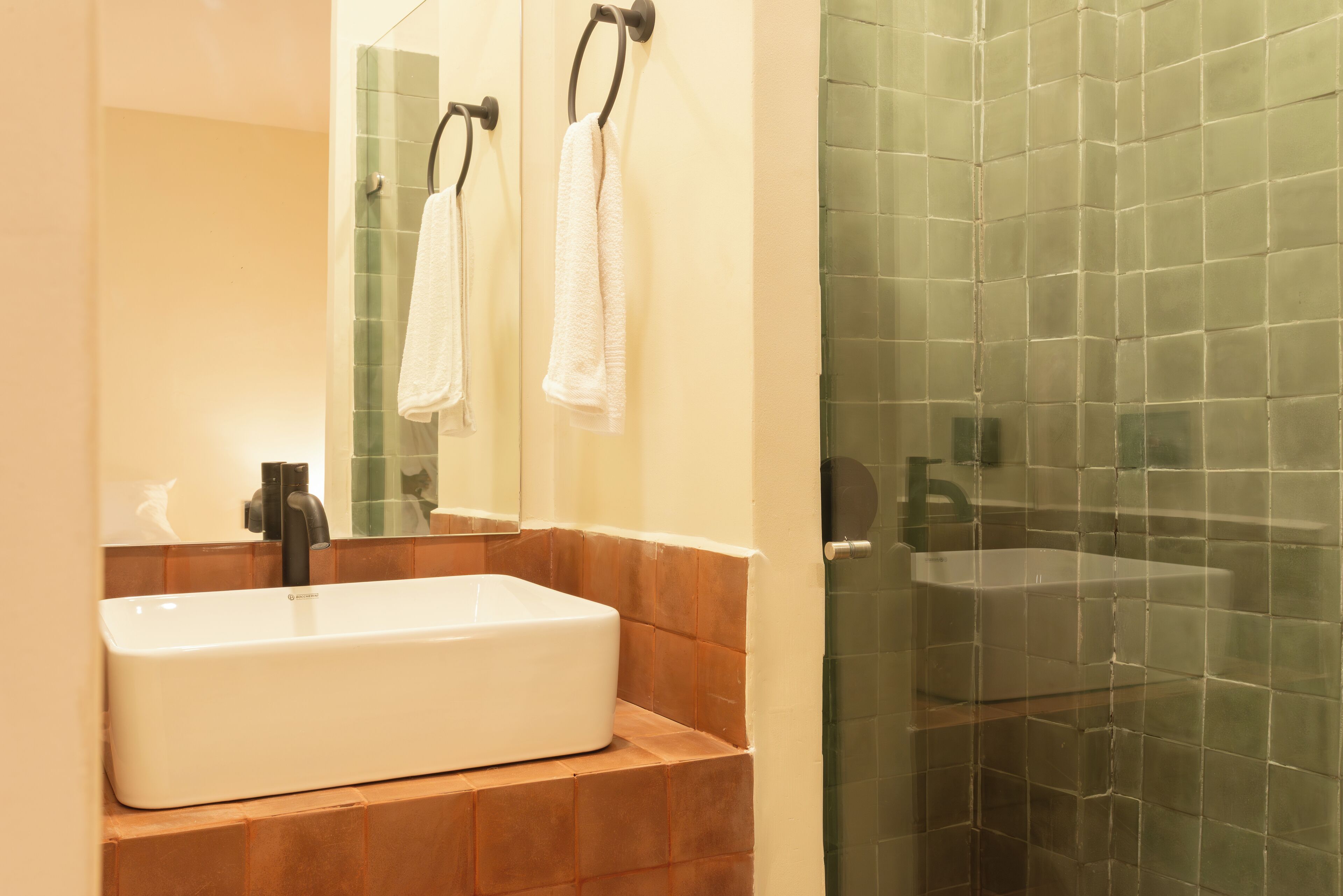 A bathroom with a white sink, a mirror, and a glass shower enclosure.