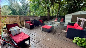 A wooden deck with outdoor furniture, including chairs and a sofa, surrounded by trees. - Suarez Art Stay Coconut Grove Miami Home with free Parking    (Miami)