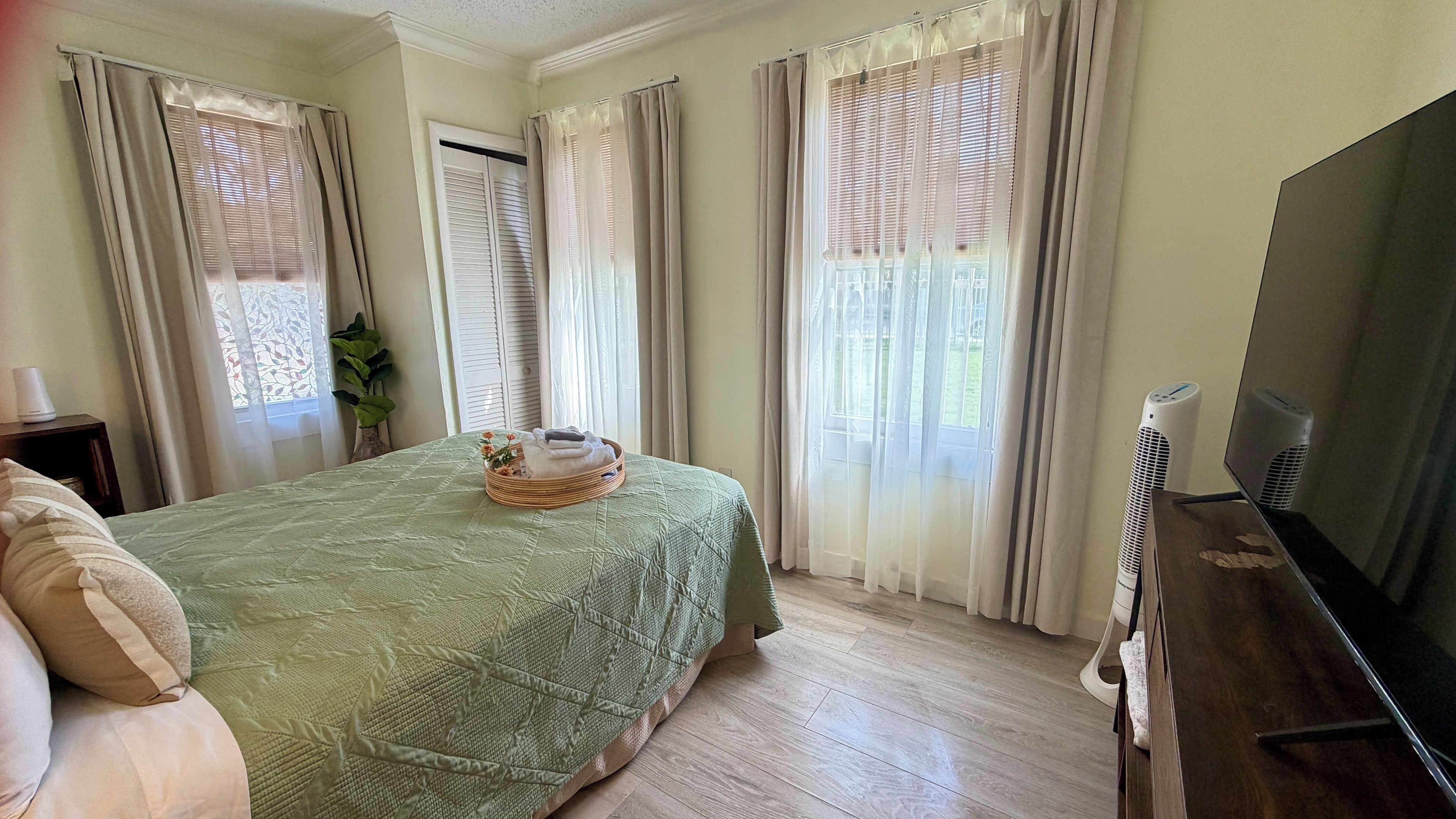 Un dormitorio con cama, televisión y ventana con cortinas.