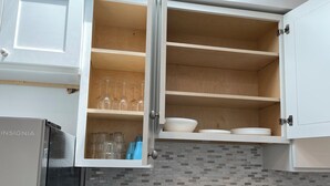 A kitchen with open cabinets displaying glassware and bowls, a stainless steel refrigerator, and a tiled backsplash. - P3E. Near MET Peaceful 2-bedrooms 2 bathrooms entire apartment. (Philadelphia)