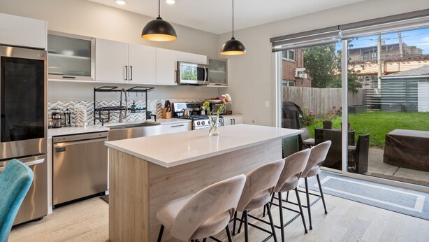 A modern kitchen with a central island, stainless steel appliances, and a sliding glass door leading to a backyard. - Discover the Heart of Chicago from Our Modern 3 Bed/ 2.5 Bath Home (Chicago)
