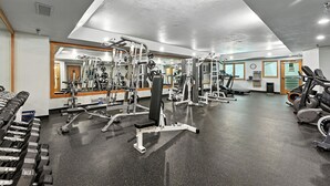 A gym with various exercise equipment, including dumbbells, a bench press, and cardio machines. - Ski in/ski out condo at Winter Park - cozy slopeside with pool, hot tub & more (Winter Park)