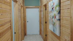 A hallway with wooden walls and a tiled floor, leading to a closed door at the end. - Pleasant 3-bedroom bungalow with AC in charming Clearfield (Clearfield)
