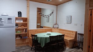A cozy room with a wooden bench, a table with chairs, a refrigerator, and shelves with books and decorative items. - Pleasant 3-bedroom bungalow with AC in charming Clearfield (Clearfield)