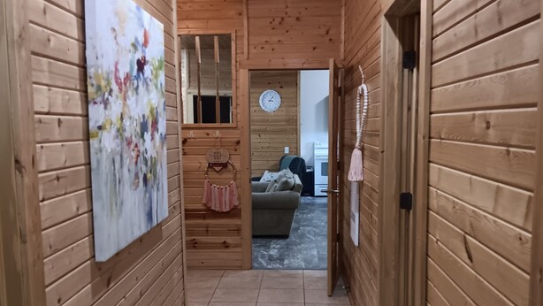 A wooden hallway with a painting on the left, a mirror, and a door on the right. - Pleasant 3-bedroom bungalow with AC in charming Clearfield (Clearfield)