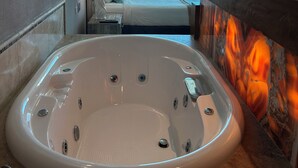 A modern bathroom with a large bathtub, a ceiling fan, and a view of the ocean through large windows. - Tessoro 802 Oceanfront Luxury Condo (Las Conchas)