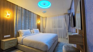 Een moderne slaapkamer met een groot bed, een nachtkastje, een spiegel en een plafondlamp.