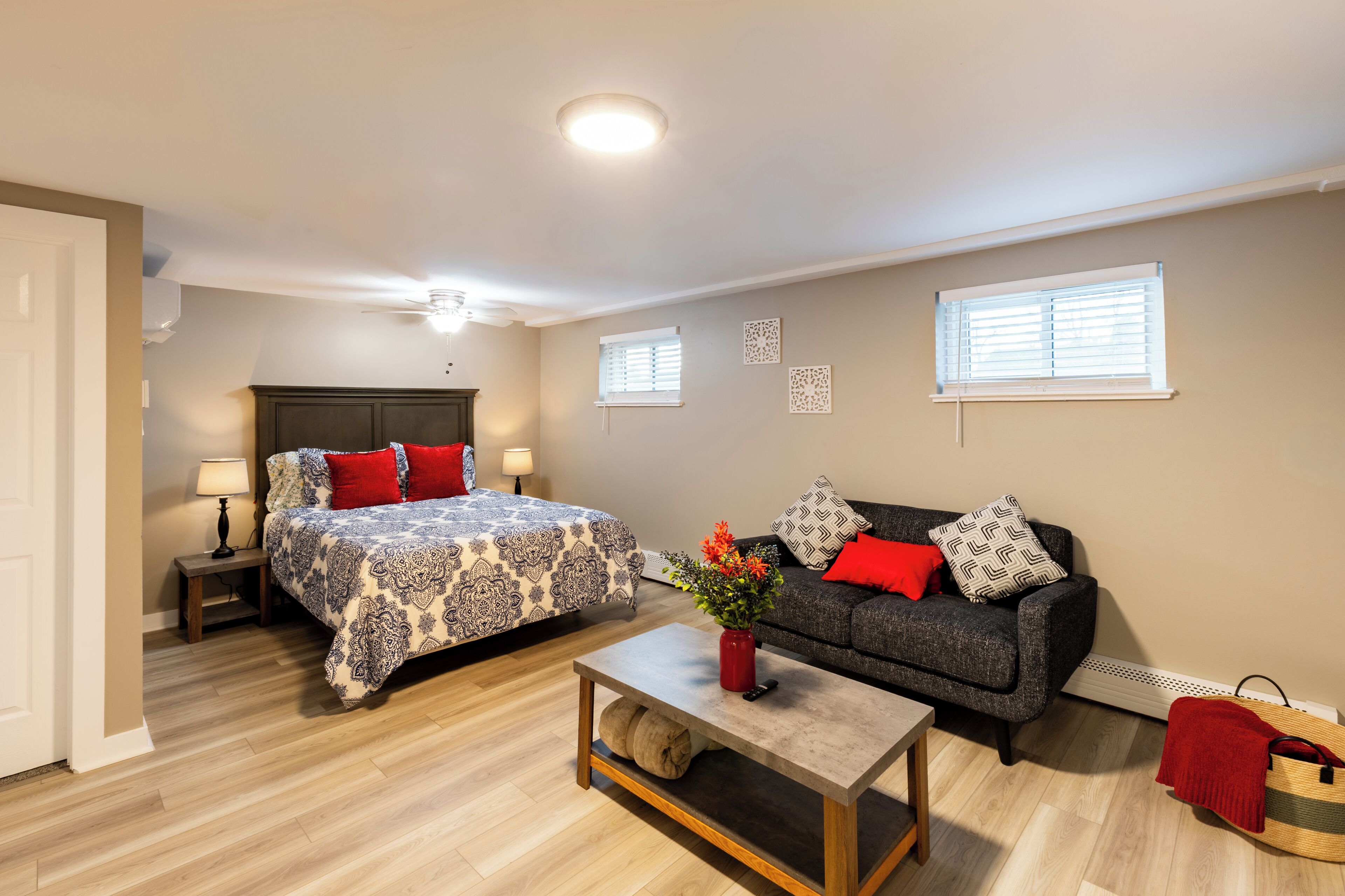 Une chambre à coucher avec un lit, une table de chevet, une lampe et une petite table sur laquelle est posé un vase.