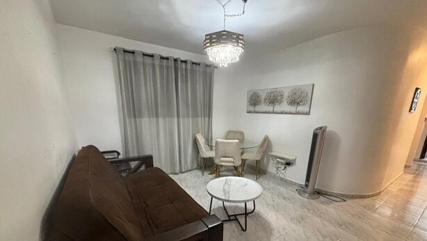 A living room with a brown sofa, a round coffee table, and a chandelier.