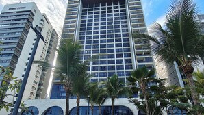 A modern hotel with a central courtyard, featuring a pool area with lounge chairs and palm trees. - Premium Flat Golden Beach Beachfront Piedade (Jaboatão dos Guararapes)