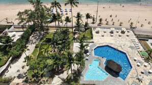 A resort with a swimming pool, beach, and palm trees. - Premium Flat Golden Beach Beachfront Piedade (Jaboatão dos Guararapes)