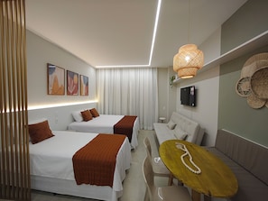 A modern hotel room with two beds, a sofa, a TV, and a small table.