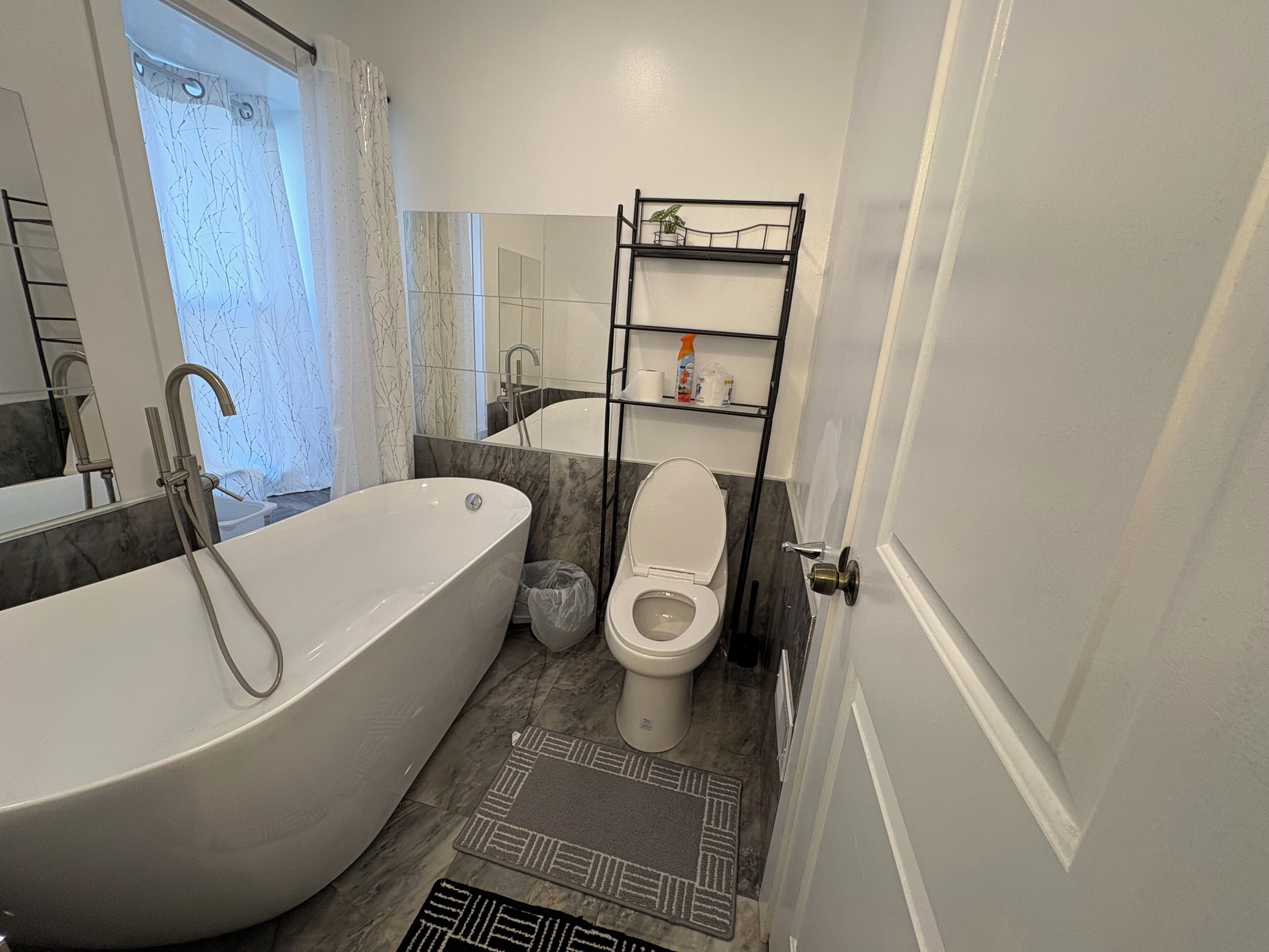 Un bagno con una vasca freestanding, un water, una doccia e uno scaffale con articoli da toilette.