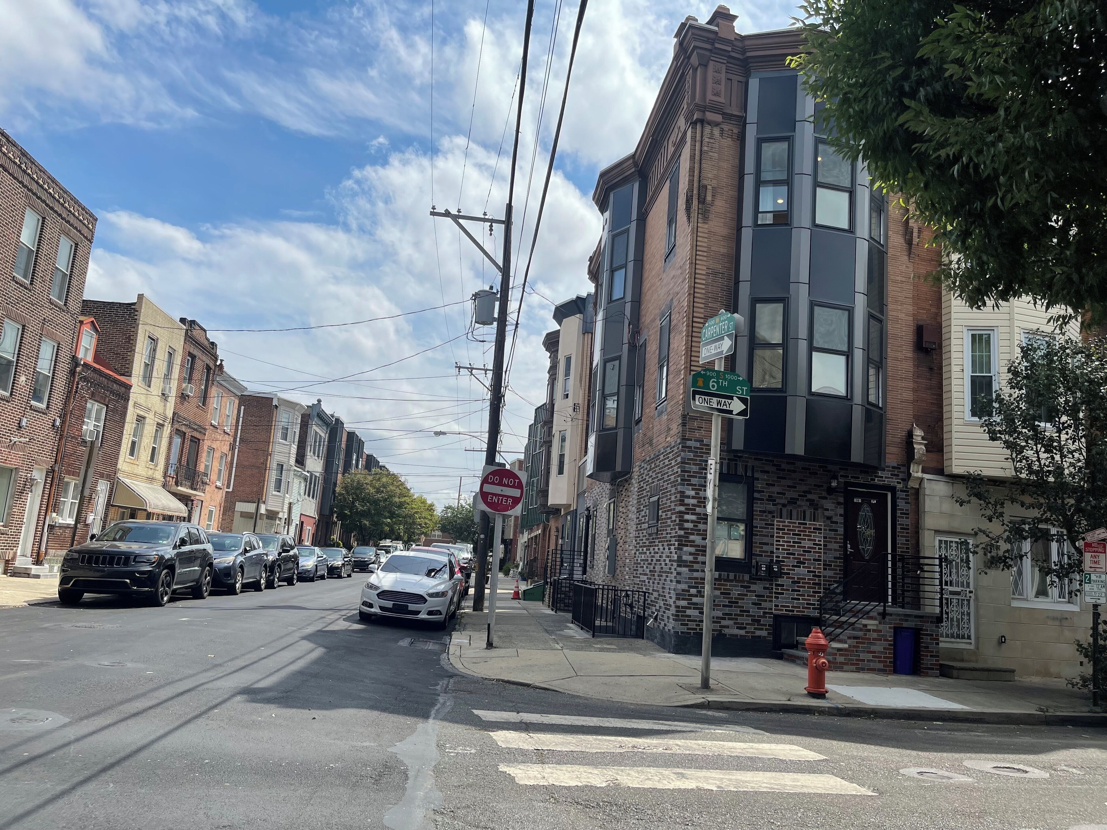 Une vue de rue avec des immeubles à plusieurs étages, un panneau indiquant « accès interdit » et des voitures garées.