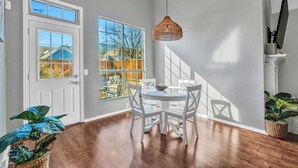A dining area with a white table and chairs, a woven pendant light, and a view of a backyard through large windows. - Modern Texas Home. Prime Frisco Location (Frisco)