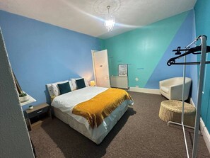 Une chambre à coucher avec un lit, une table de chevet, une lampe et une chaise.