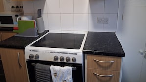 Una cocina con estufa, horno, microondas y alacenas.