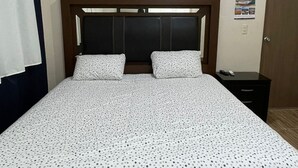 A single bed with a wooden frame and a dark headboard, a small bedside table, and a wall-mounted light switch. - Serene 3-bedroom apartment with AC in Puerto Escondido (Puerto Escondido)
