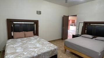 A bedroom with two beds, a ceiling fan, and a light fixture.