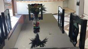 A dining area with a table, chairs, a vase with flowers, and a kitchen in the background. - Serene 3-bedroom apartment with AC in Puerto Escondido (Puerto Escondido)