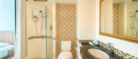 A modern bathroom with a glass shower enclosure, a toilet, a sink, and a large mirror.