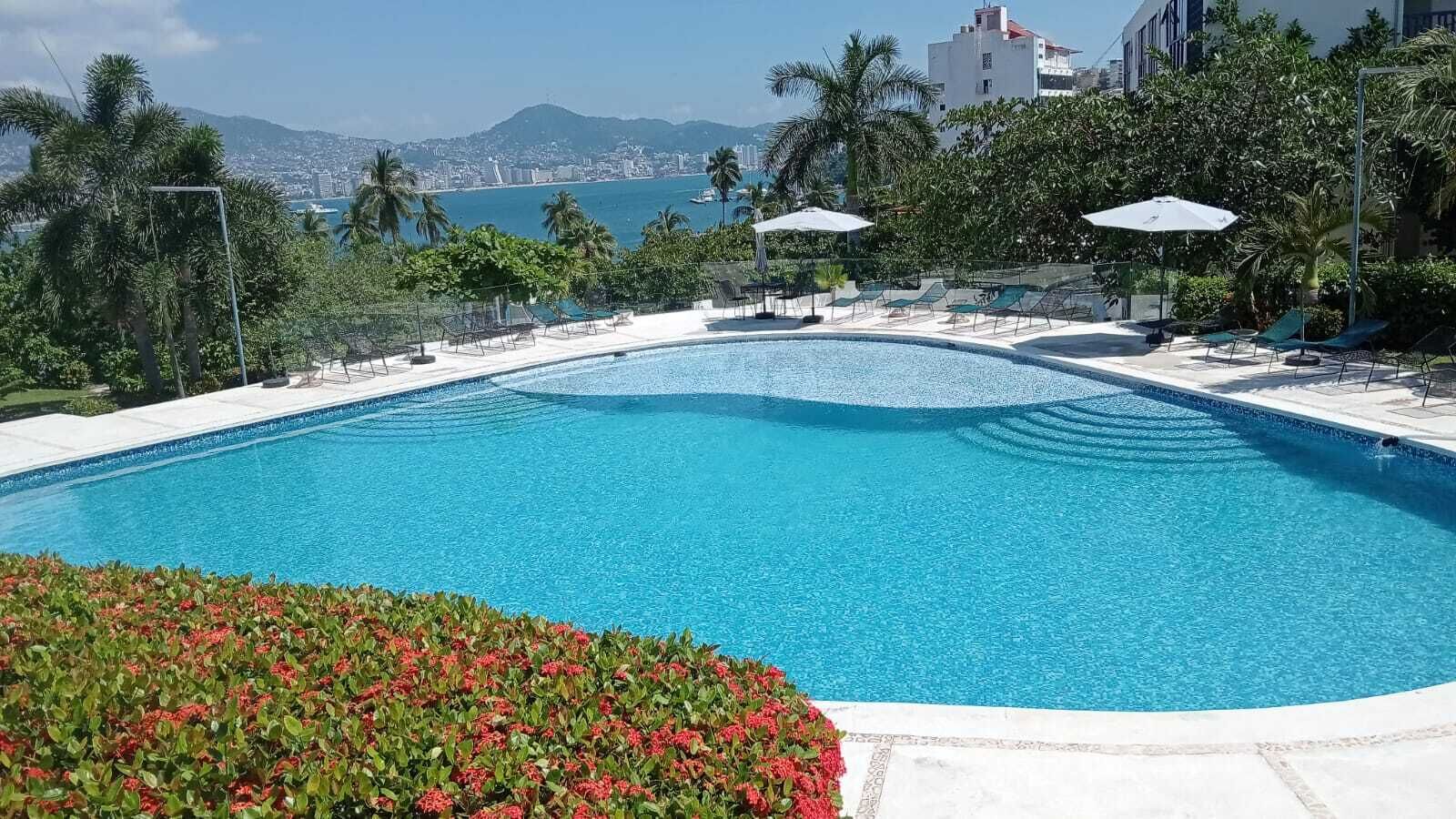A swimming pool with a view of the city and mountains in the background.