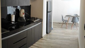 A modern kitchen with dark cabinetry, a gas stove, and a stainless steel refrigerator. - Beautiful apartment in Residencial Astorias! (Acapulco de Juárez)