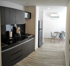 A modern kitchen with dark cabinetry, a gas stove, and a stainless steel refrigerator.