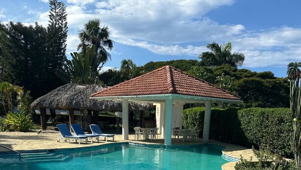 A clear blue pool with lounge chairs and a gazebo. - Enjoyable 1-bedroom apartment with AC in vibrant Sosúa (Sosúa)