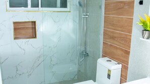 A modern bathroom with a glass-enclosed shower, a toilet, and a sink. - Enjoyable 1-bedroom apartment with AC in vibrant Sosúa (Sosúa)