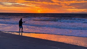 Iemand vist op het strand tijdens de zonsondergang.