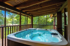 A hot tub in a wooden deck area with a view of trees. - Private 1-Acre Gatlinburg Cabin / Hot Tub, Theater & Game Room (Gatlinburg)