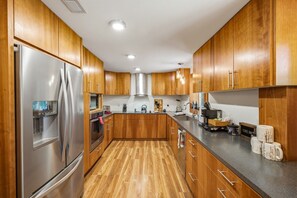 A modern kitchen with wooden cabinets, stainless steel appliances, and a granite countertop. - Private 1-Acre Gatlinburg Cabin / Hot Tub, Theater & Game Room (Gatlinburg)