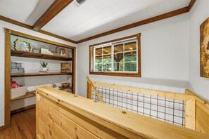A room with wooden beams, a window with a view of greenery, a shelf with decorative items, and a wooden bench. - Private 1-Acre Gatlinburg Cabin / Hot Tub, Theater & Game Room (Gatlinburg)